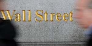 Des personnes passent devant un panneau wall street pres de la bourse de new york