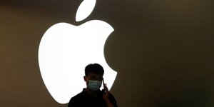 Un homme parle au telephone devant le logo d'apple a l'exterieur d'un magasin a shanghai
